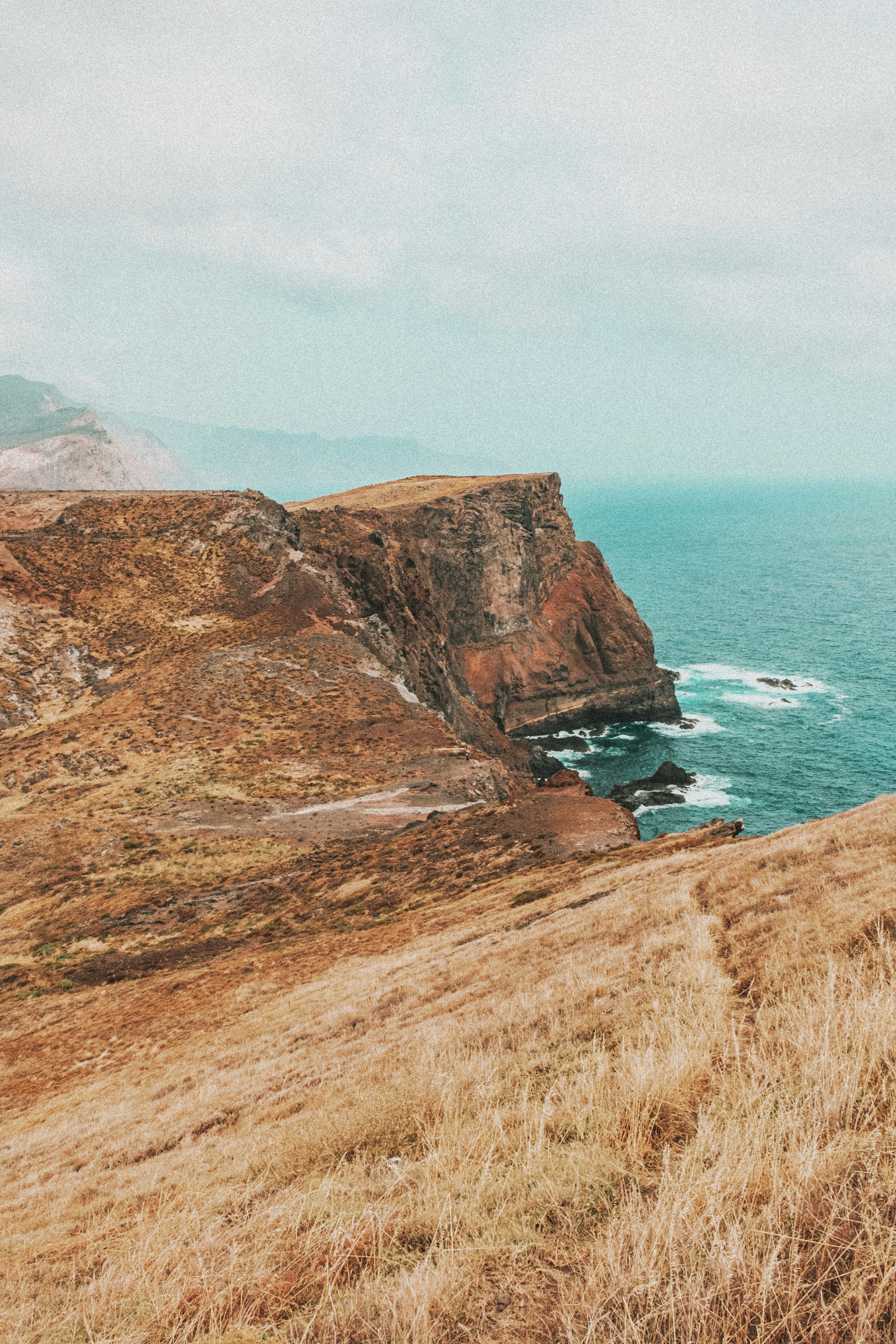 brown and green mountain beside body of water during daytime